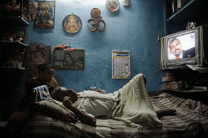 An Indian man and his daughter-in-law watch television at their home in Dharavi in 2008. Residents of Dharavi fear they will be moved from their existing homes to the outskirts of Mumbai when slum redevelopment plans go ahead.