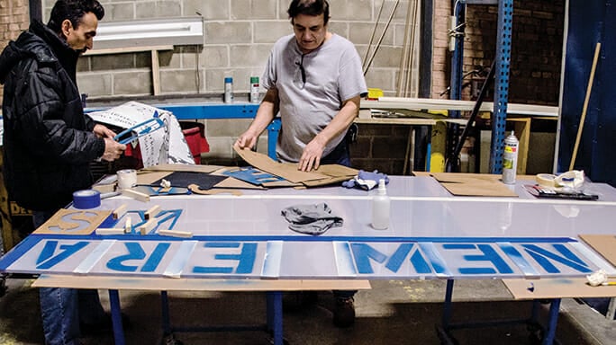 Rodolfo Zoto and Norberto Román make signage for the New Era Windows plant.