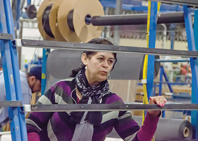 New Era worker Beatriz Gurrola installs window hardware.